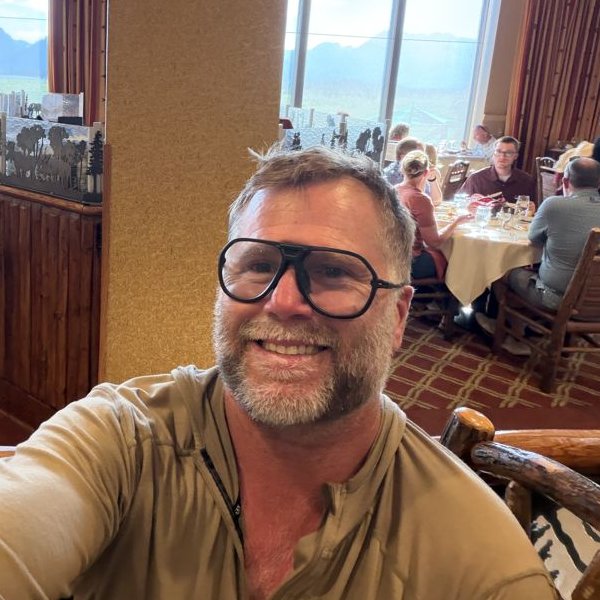 Joe Shelton smiling at Jackson Lake Lodge with the Tetons out the window